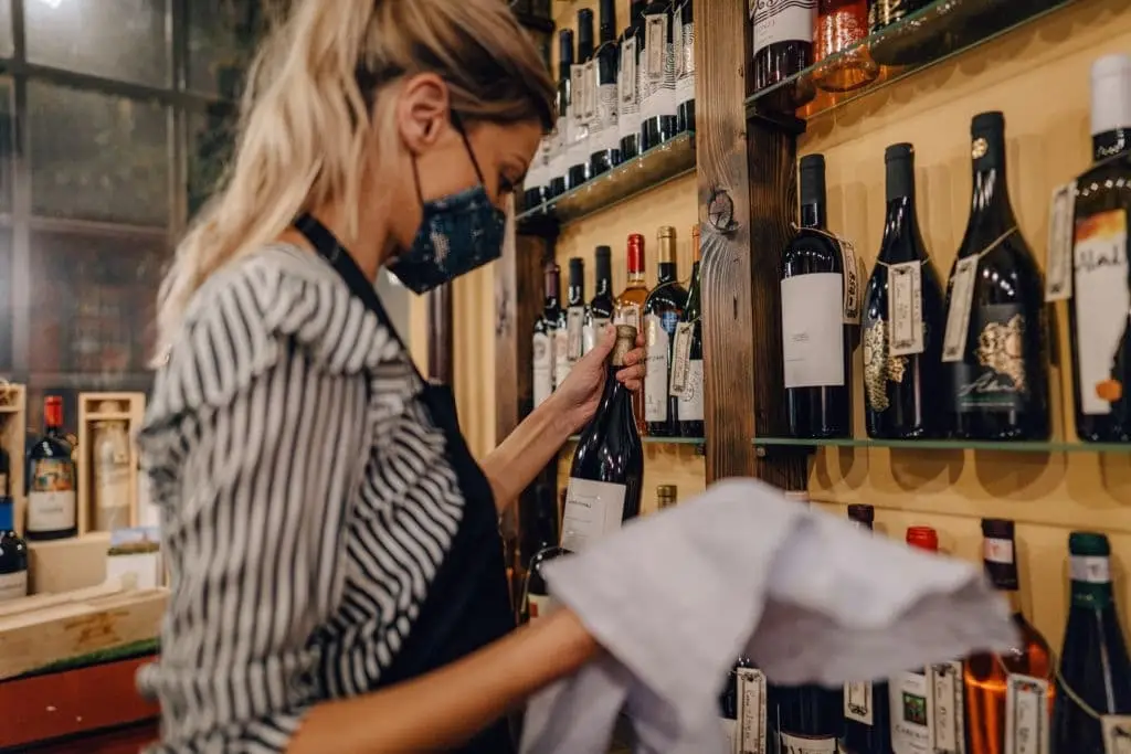 woman cleaning bottle of wines